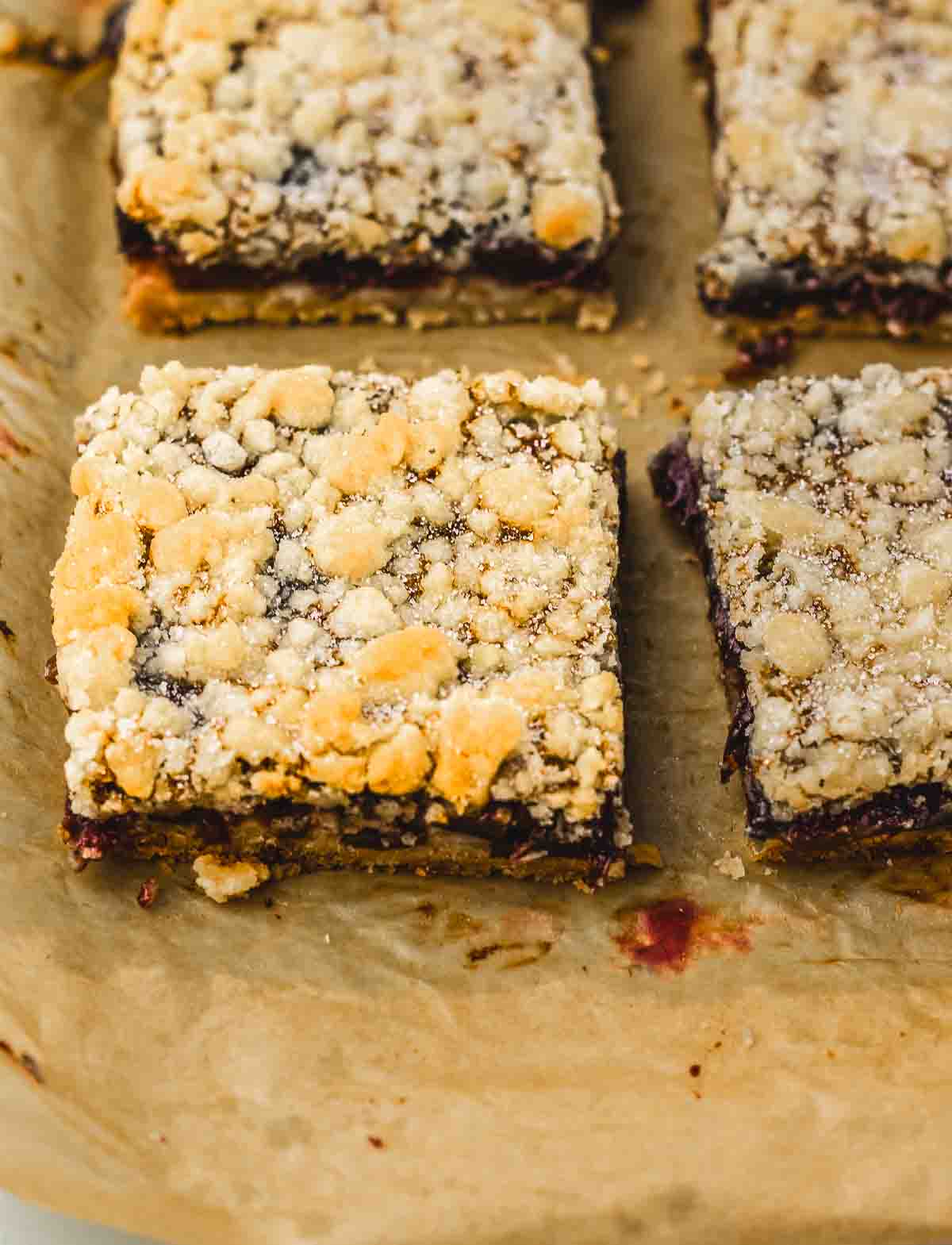 Close-up of crumb bars with a golden topping on parchment paper, reminiscent of a homemade cherry pie recipe.