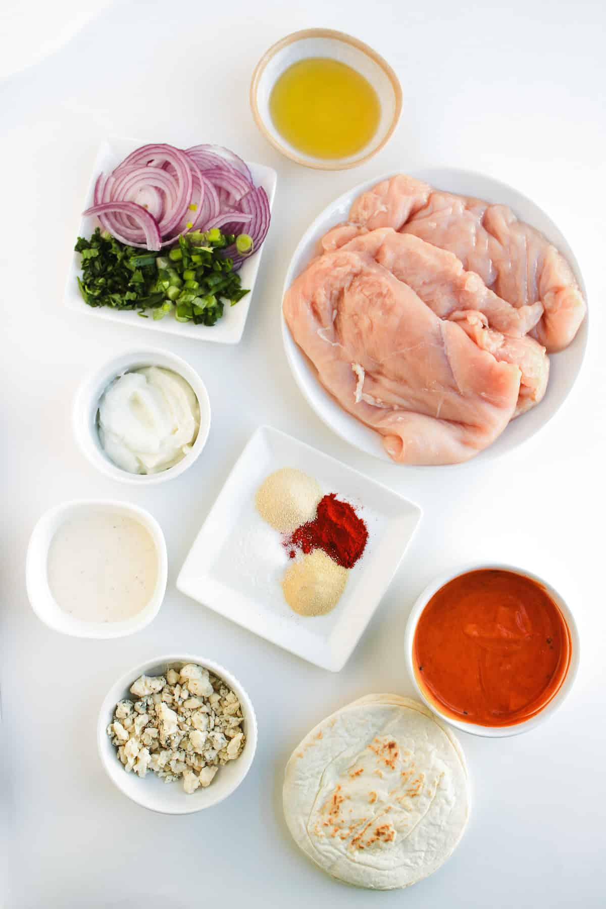 Ingredients for chicken wrap: raw chicken, seasonings, sauces, sliced onions, herbs, cheese, yogurt, and tortillas—perfect for making Easy Tacos or flavorful Chicken Tacos at home.