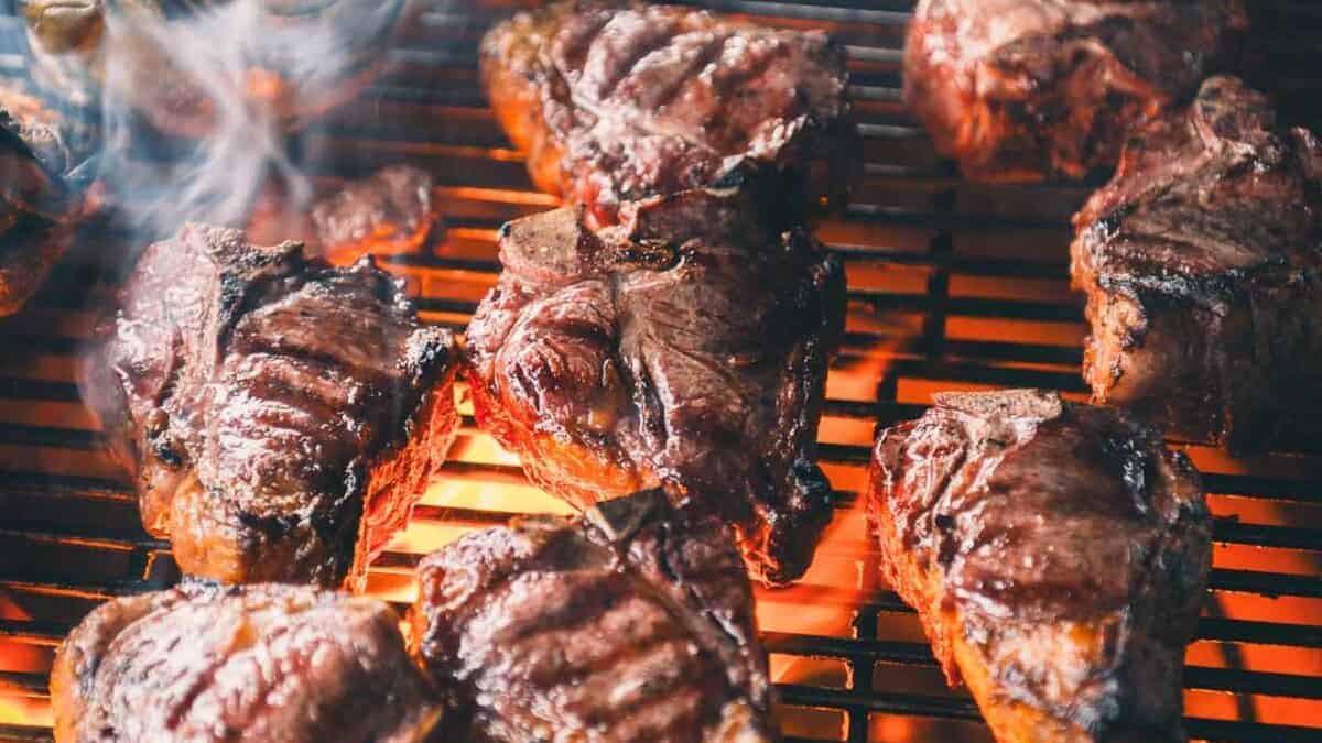 Grilled lamb loin chops with charred edges and fresh herbs scattered across the serving platter.