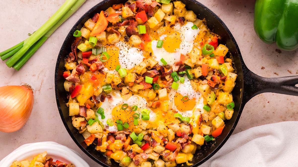 Breakfast skillet with eggs, potatoes, and vegetables.