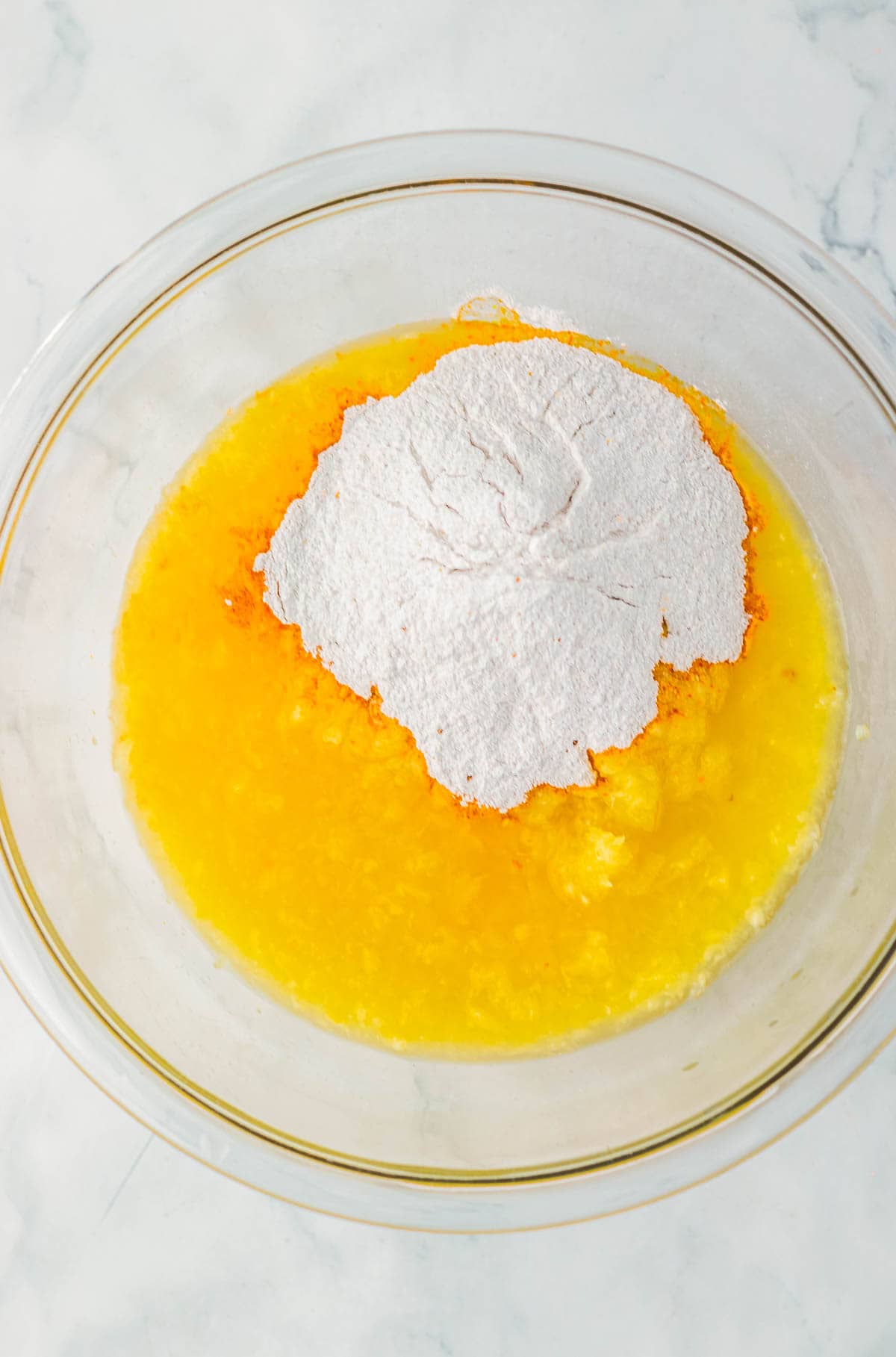 A glass bowl with melted butter and a mound of flour on top, ready for mixing—perfect for creating the base of a delicious caramel apple fluff dessert.