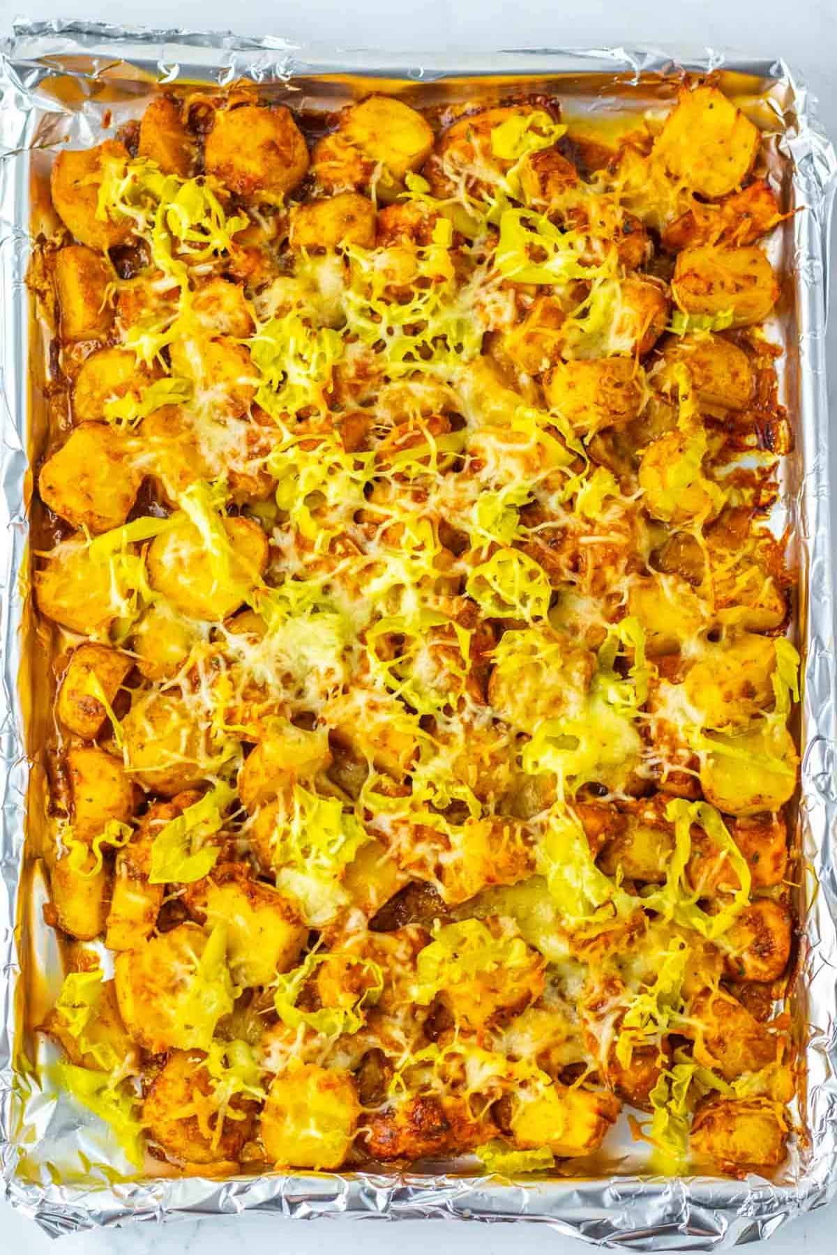 Sheet pan filled with roasted potatoes, shredded cheese, and yellow pepper slices on aluminum foil&mdash;perfectly inspired by Sheet Pan Mississippi Chicken and Potatoes for a hearty, flavorful meal.