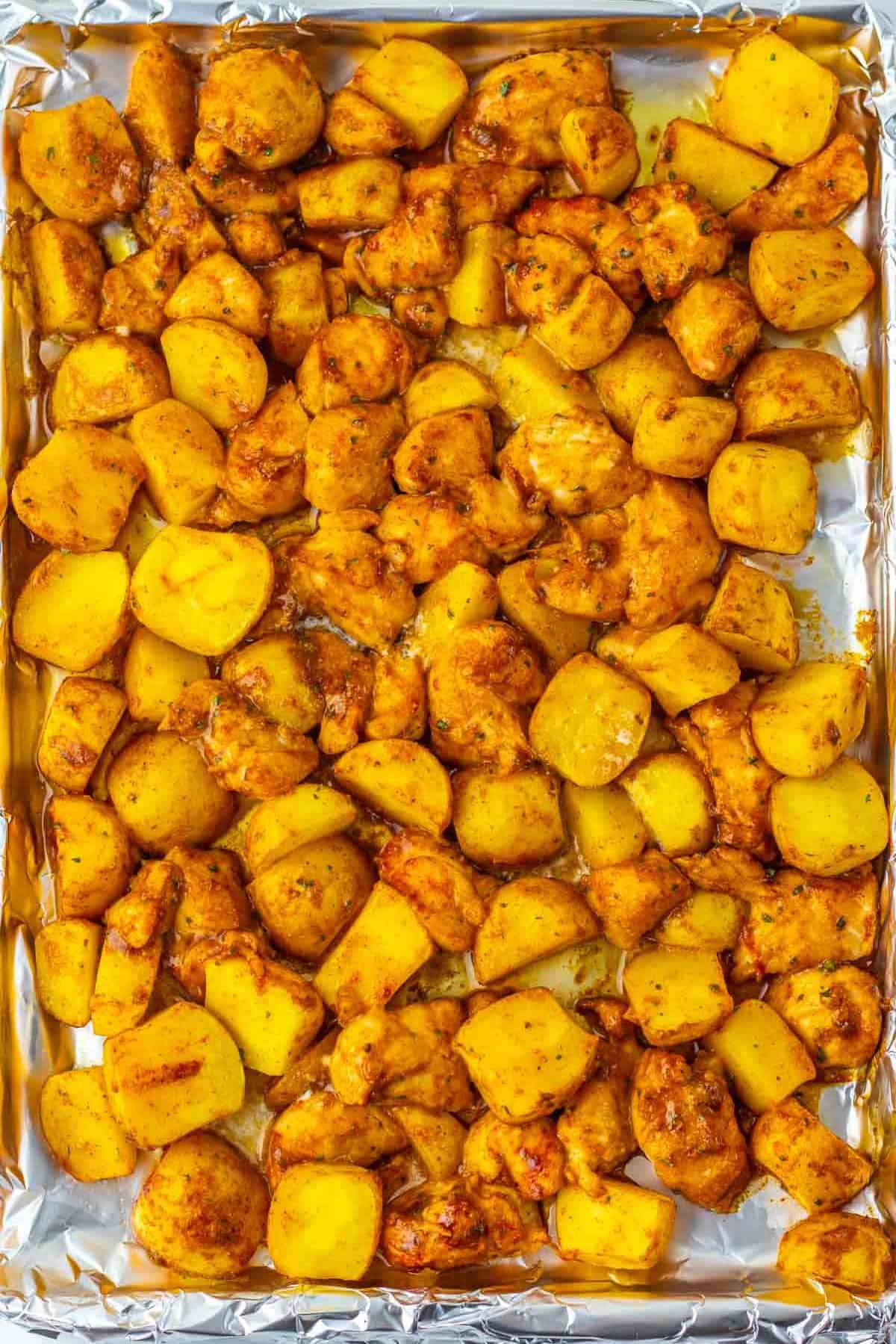 Sheet Pan Mississippi Chicken and Potatoes features roasted chicken and potato pieces seasoned with spices on a foil-lined baking sheet.