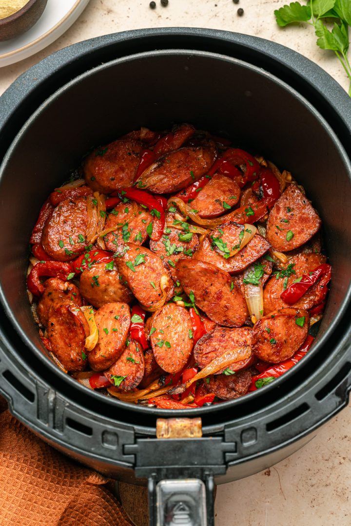 Sliced air fryer kielbasa with red peppers and onions cooked to perfection, garnished with chopped parsley.