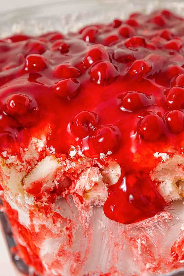 Close-up of a vintage Cherries in the Snow Dessert, featuring red cherries and glaze over creamy, layered filling and bits of crust.