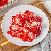 Vintage Cherries in the Snow Dessert featuring a creamy filling, elegantly served on a white plate, placed on a wooden board and white surface.