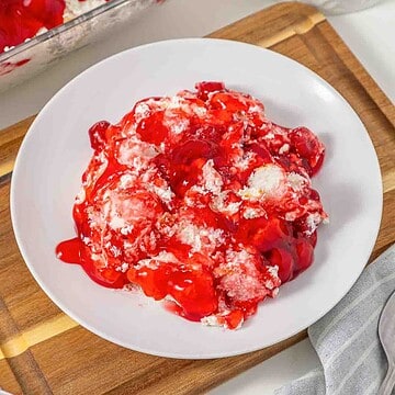 Vintage Cherries in the Snow Dessert featuring a creamy filling, elegantly served on a white plate, placed on a wooden board and white surface.