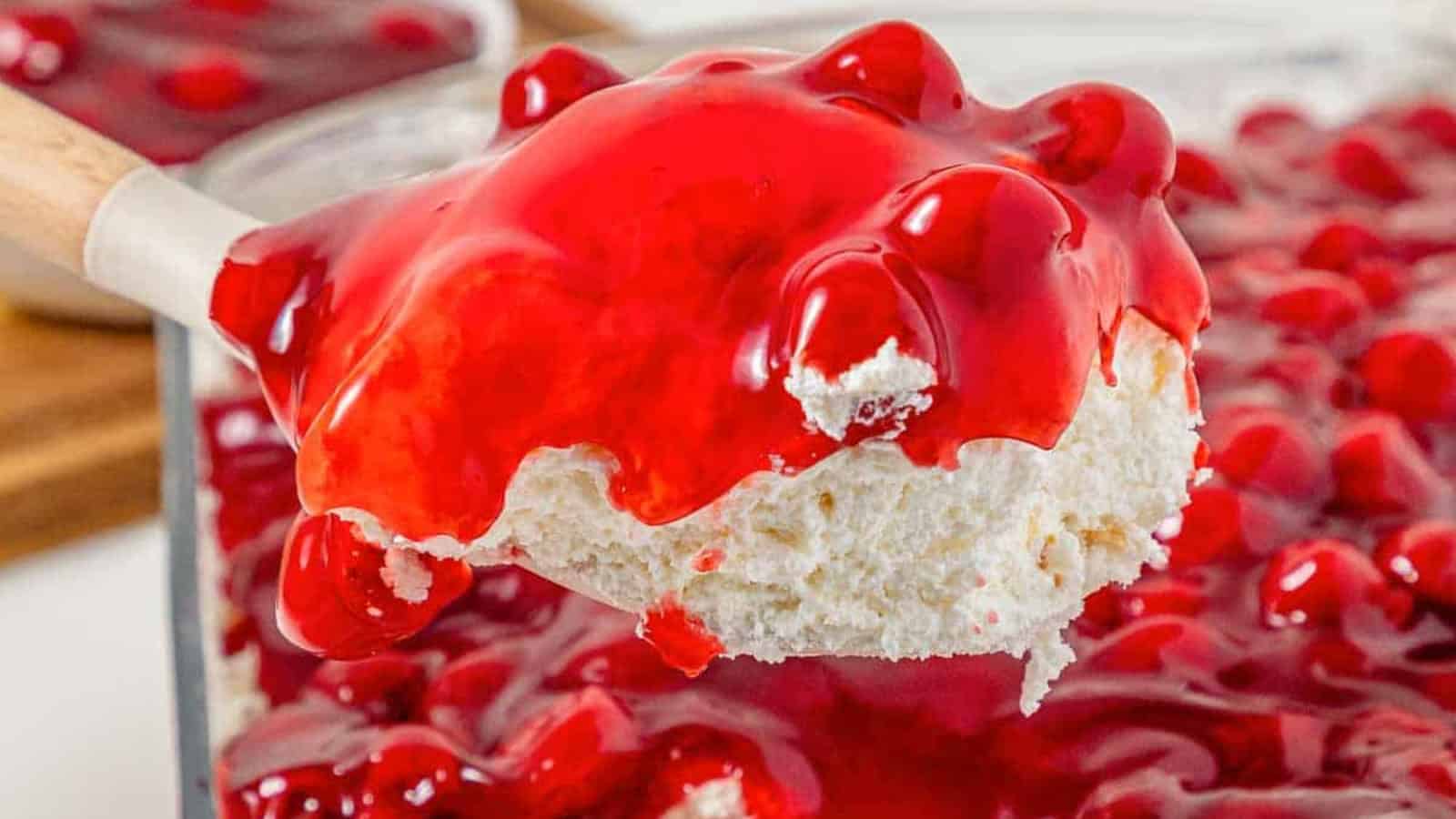 A spoonful of cherry dessert with whipped topping and bright red cherry pie filling.