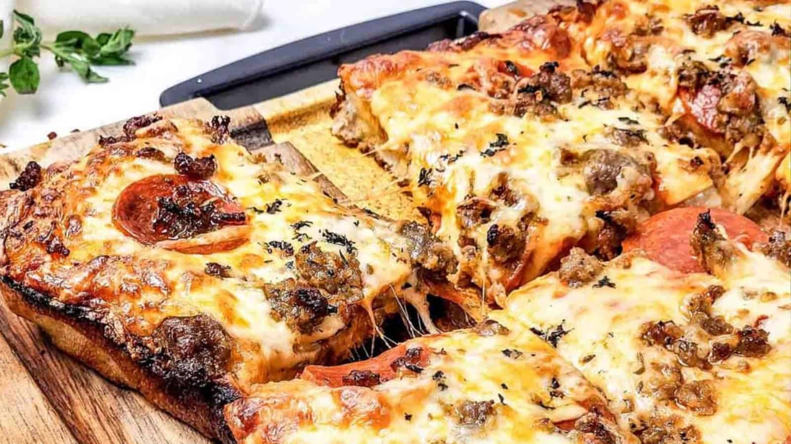 Close-up of cheesy, thick-crust pizza with pepperoni and sausage slices on a wooden board.