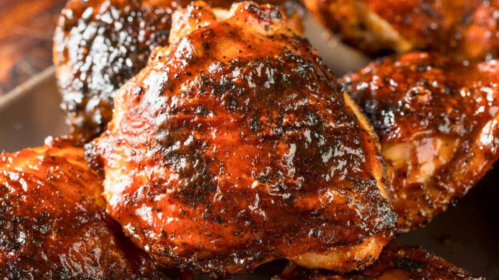 Close-up of juicy grilled chicken thighs with a shiny, caramelized barbecue glaze—perfect for Father's Day BBQ recipes hot off the grill.