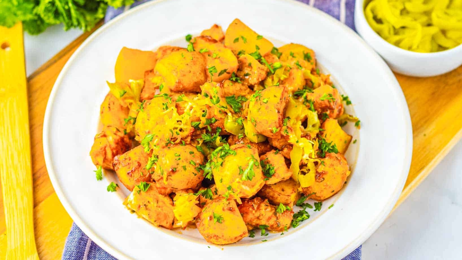 A plate of roasted potatoes garnished with chopped herbs and peppers, served on a white dish.