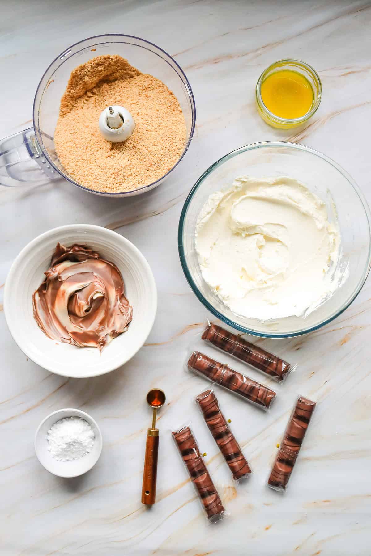 Cheesecake ingredients: cream cheese, melted butter, Nutella, cookies, sugar, chocolate bars, salt, teaspoon—everything you need to create a luscious Kinder Bueno No Bake Cake with rich layers of creamy and chocolatey goodness.