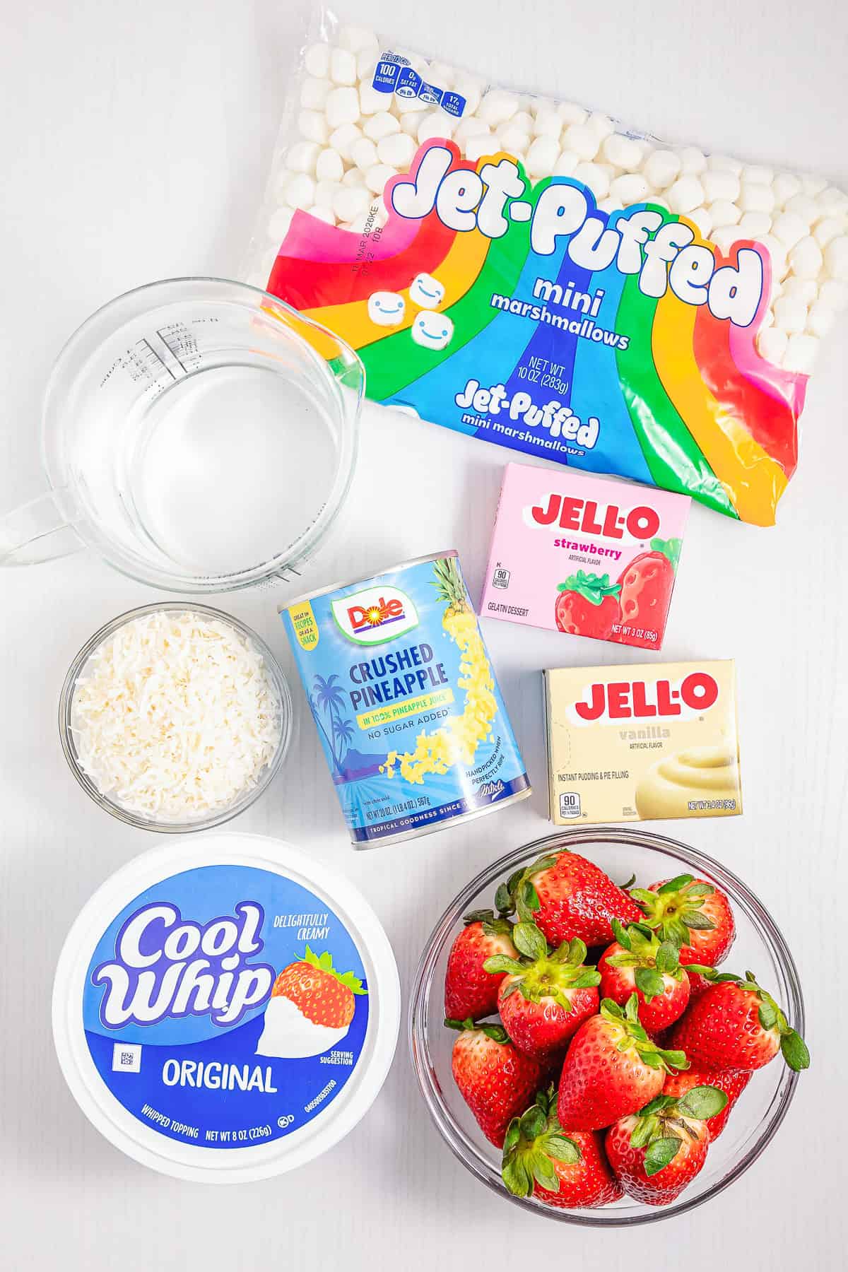 Indulge in a delightful Strawberry Fluff dessert made with Cool Whip, marshmallows, Jello, pineapple, coconut, water, and strawberries—a sweet and creamy treat perfect for any occasion.