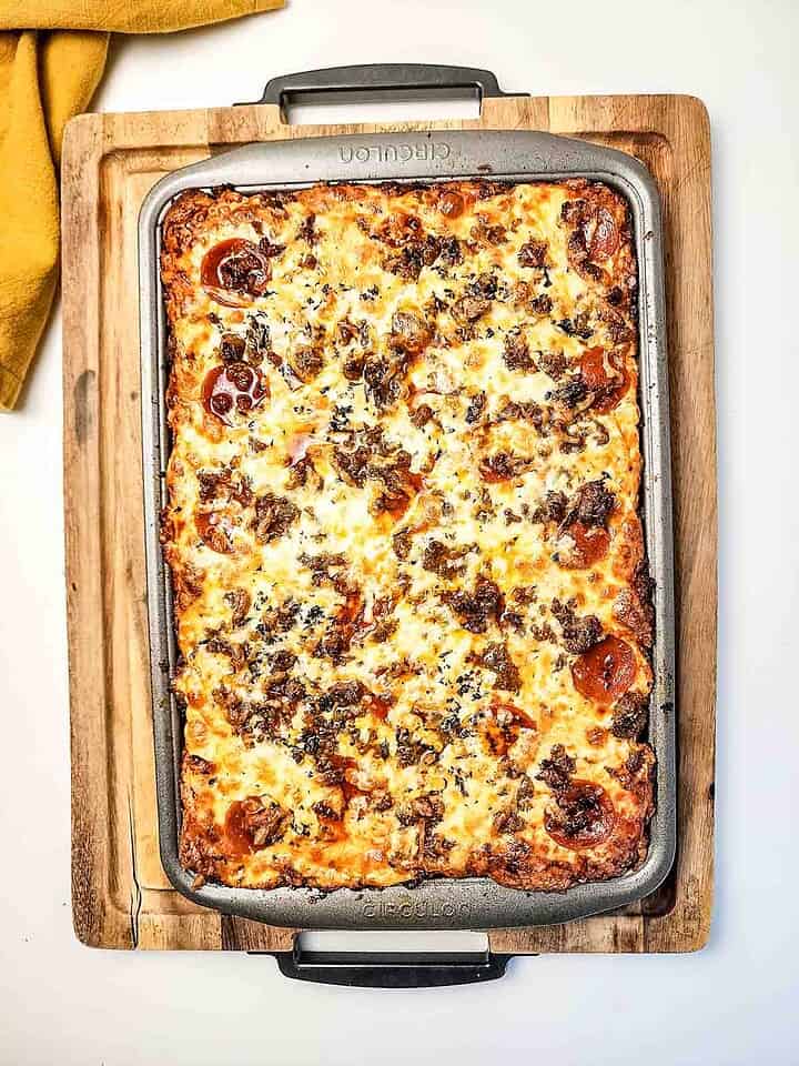 Enjoy a delicious Italian Sausage Sheet Pan Pizza&mdash;rectangular deep-dish pizza with melted cheese, savory pepperoni, flavorful Italian sausage, and fresh herbs baked to perfection on a baking tray.