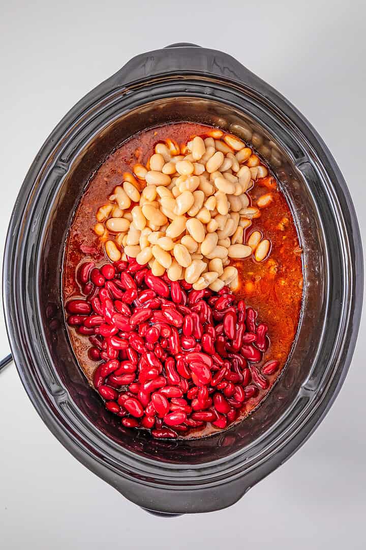 Slow Cooker Chili with Sausage, featuring red and white beans in a rich sauce, viewed from above on a white background.