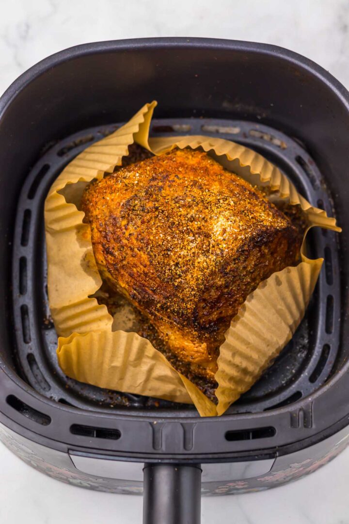 Seasoned chicken breast in parchment paper inside an air fryer basket, ready to be cooked—using the same technique that ensures a perfectly juicy Air Fryer Eye of Round Roast every time.