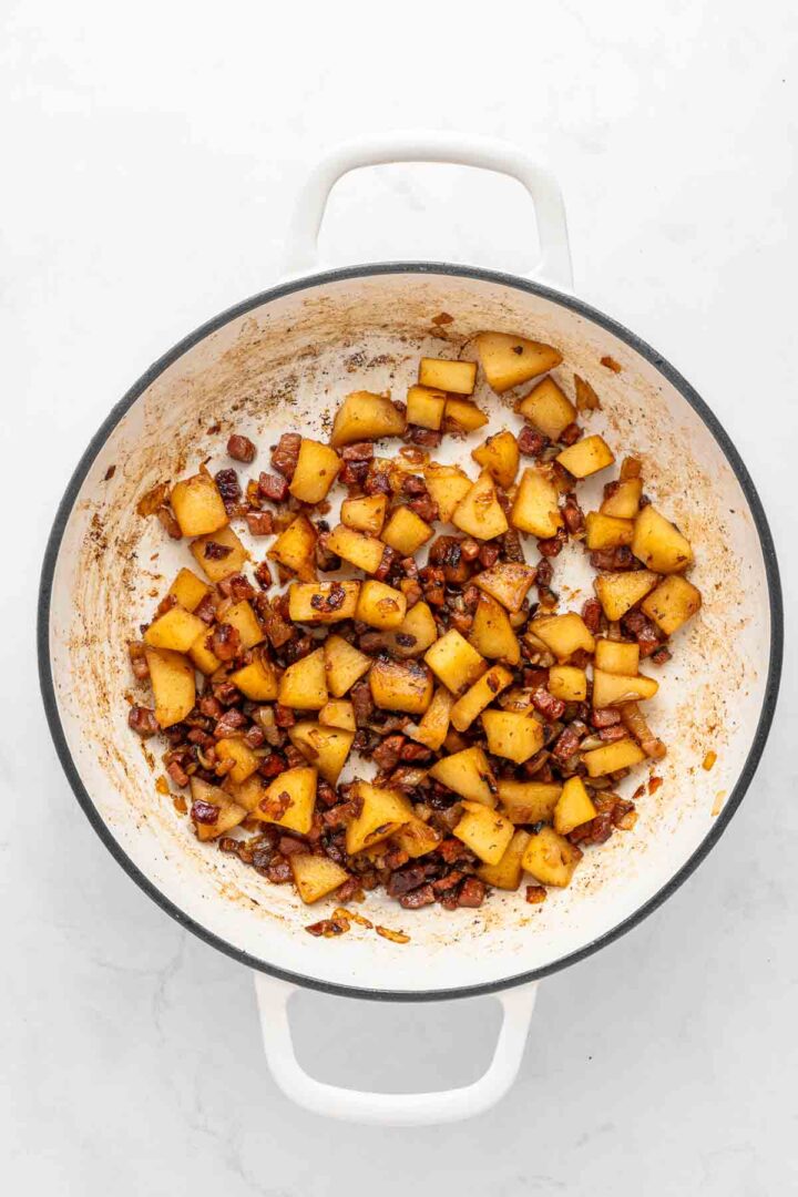 Diced apples and pecans sautéed in a white pot, coated in a light brown caramelized glaze—just like the sweet, homey aroma of Apple Pie Baked Beans.