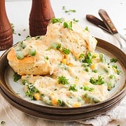 A Chicken Pot Pie with Biscuits on a plate, featuring a biscuit topped with creamy chicken and vegetable stew.