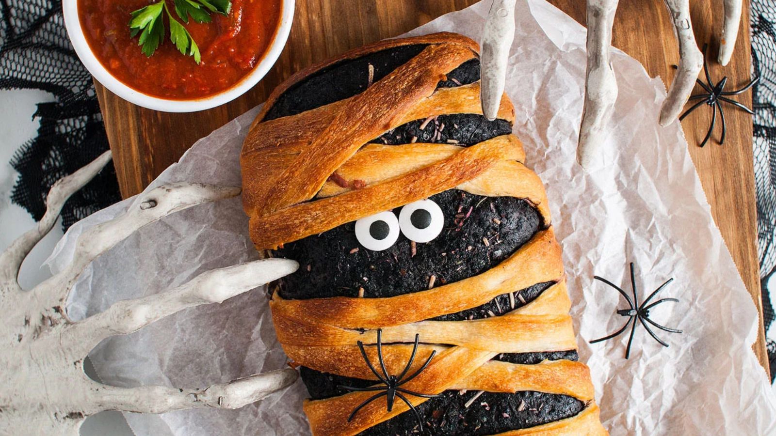 Mummy stromboli decorated with strips of dough and edible eyes.