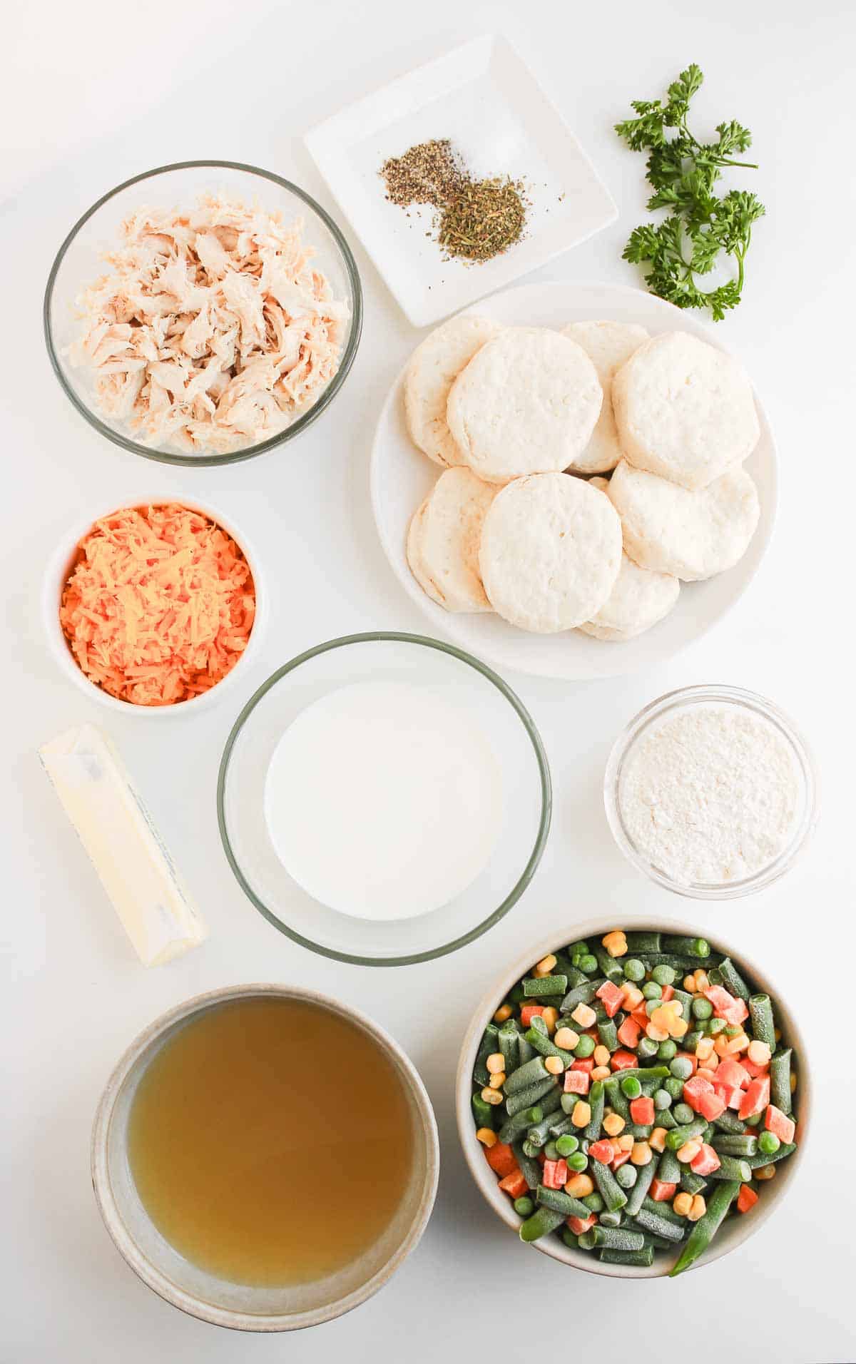 Ingredients for Chicken Pot Pie with Biscuits, including shredded chicken, vegetables, broth, milk, butter, and seasonings.