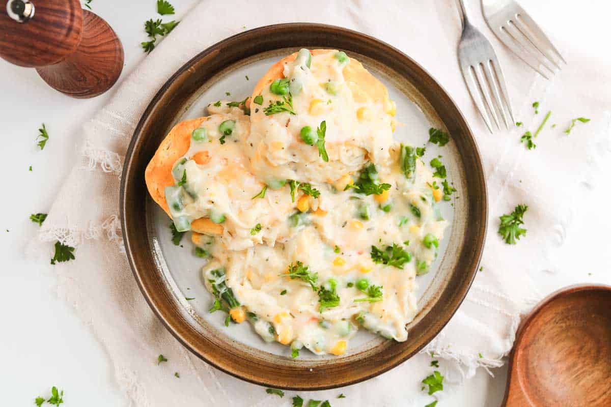 Two biscuits topped with creamy chicken pot pie gravy on a plate.