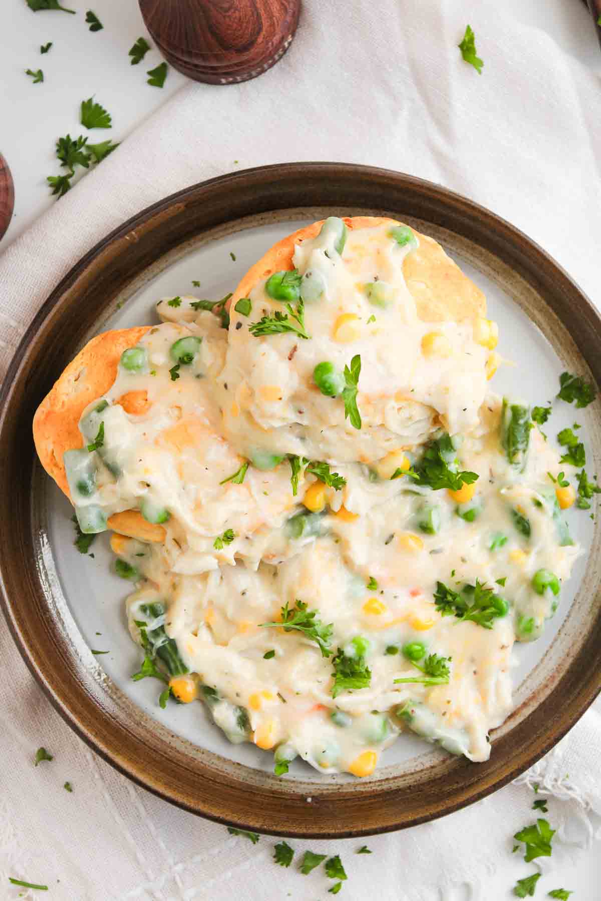Two chicken pot pie biscuits topped with creamy chicken and vegetable gravy on a plate.