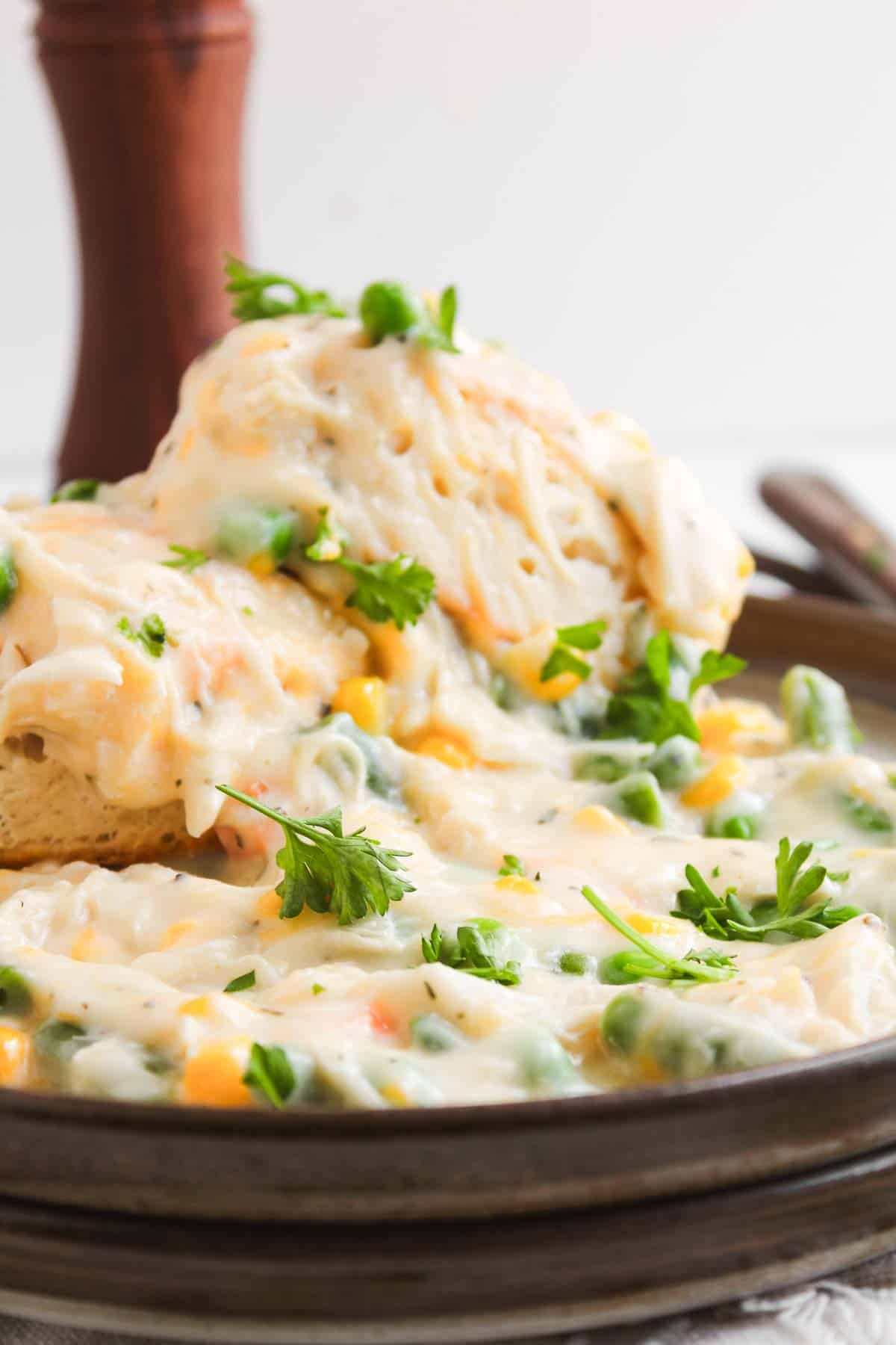 Chicken pot pie with biscuits served in a creamy sauce and garnished with fresh parsley.