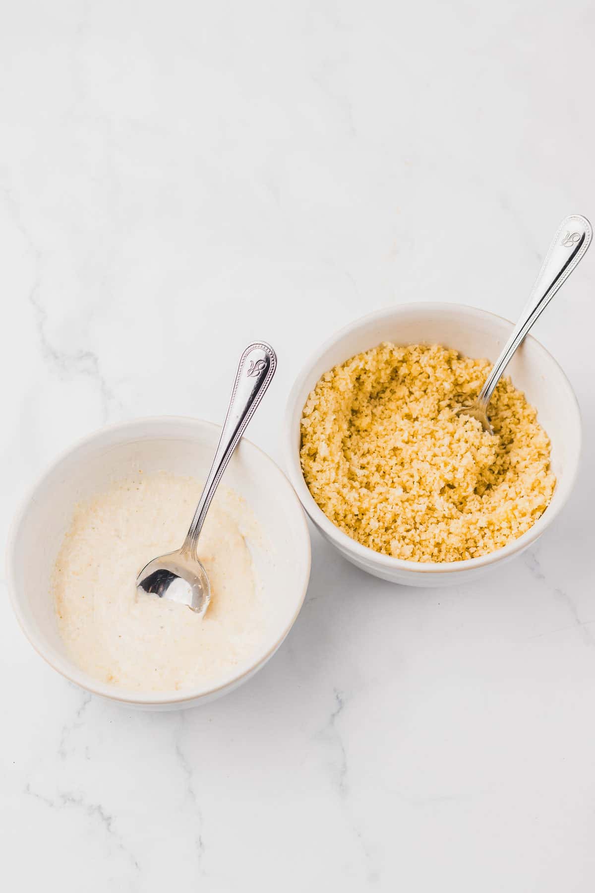 Two white bowls, one containing a creamy sauce and the other Copycat Longhorn Parmesan Crusted Chicken grains.