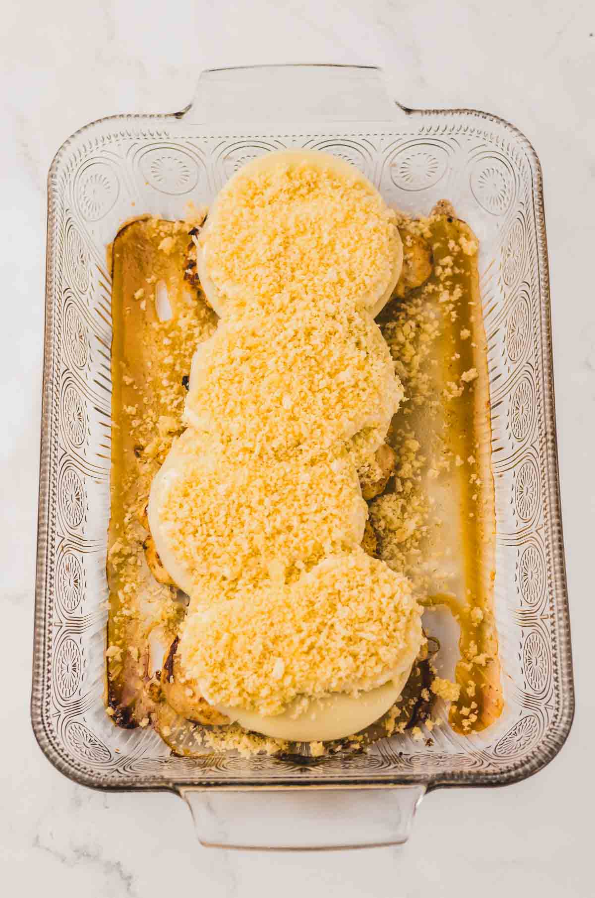 Four Longhorn Parmesan Crusted Chicken breasts topped with cheese and breadcrumbs in a glass baking dish.