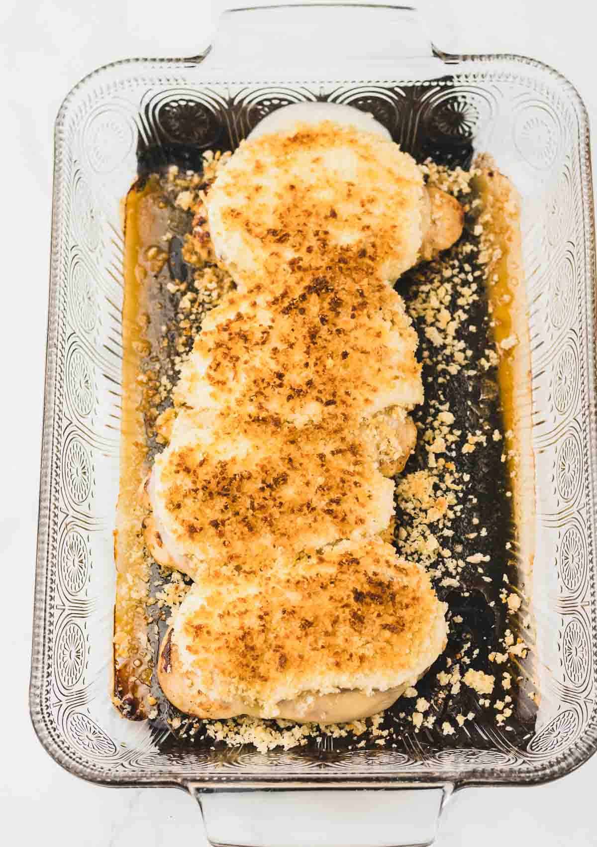 Four breaded Copycat Longhorn Parmesan Crusted Chicken breasts in a glass baking dish.