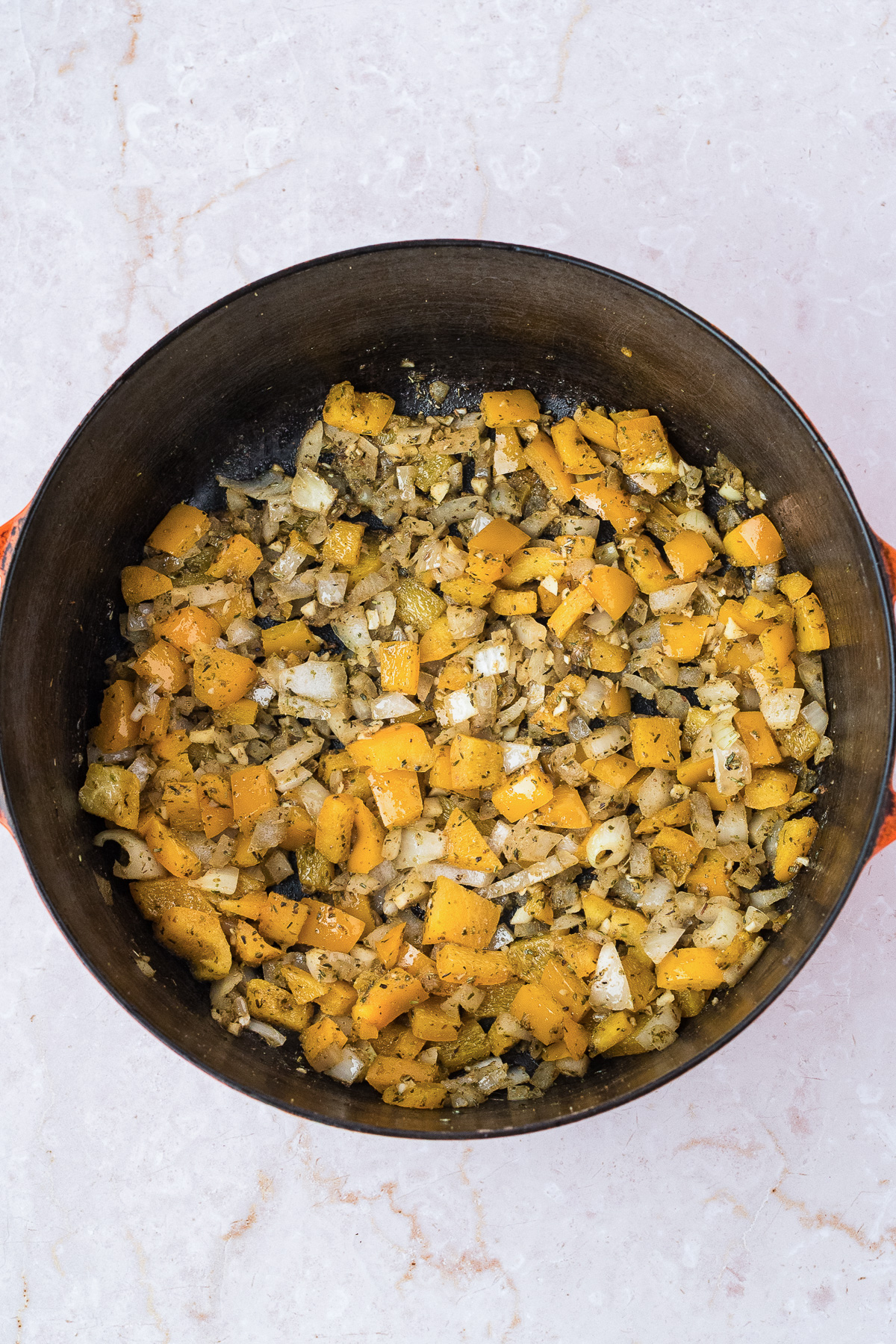 Diced yellow peppers and onions cooking in a cast iron pan for leftover turkey pumpkin chili.