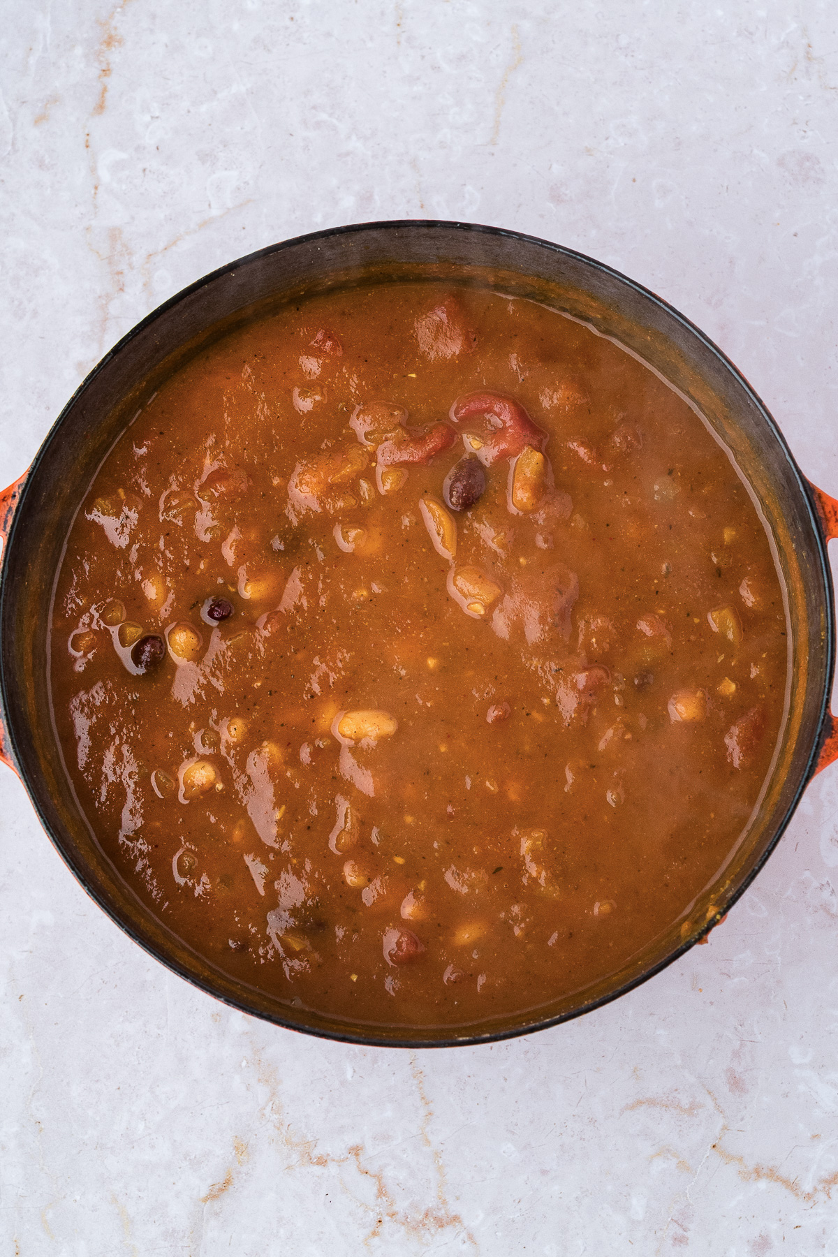 A top-down view of a pot of thick leftover turkey pumpkin chili.