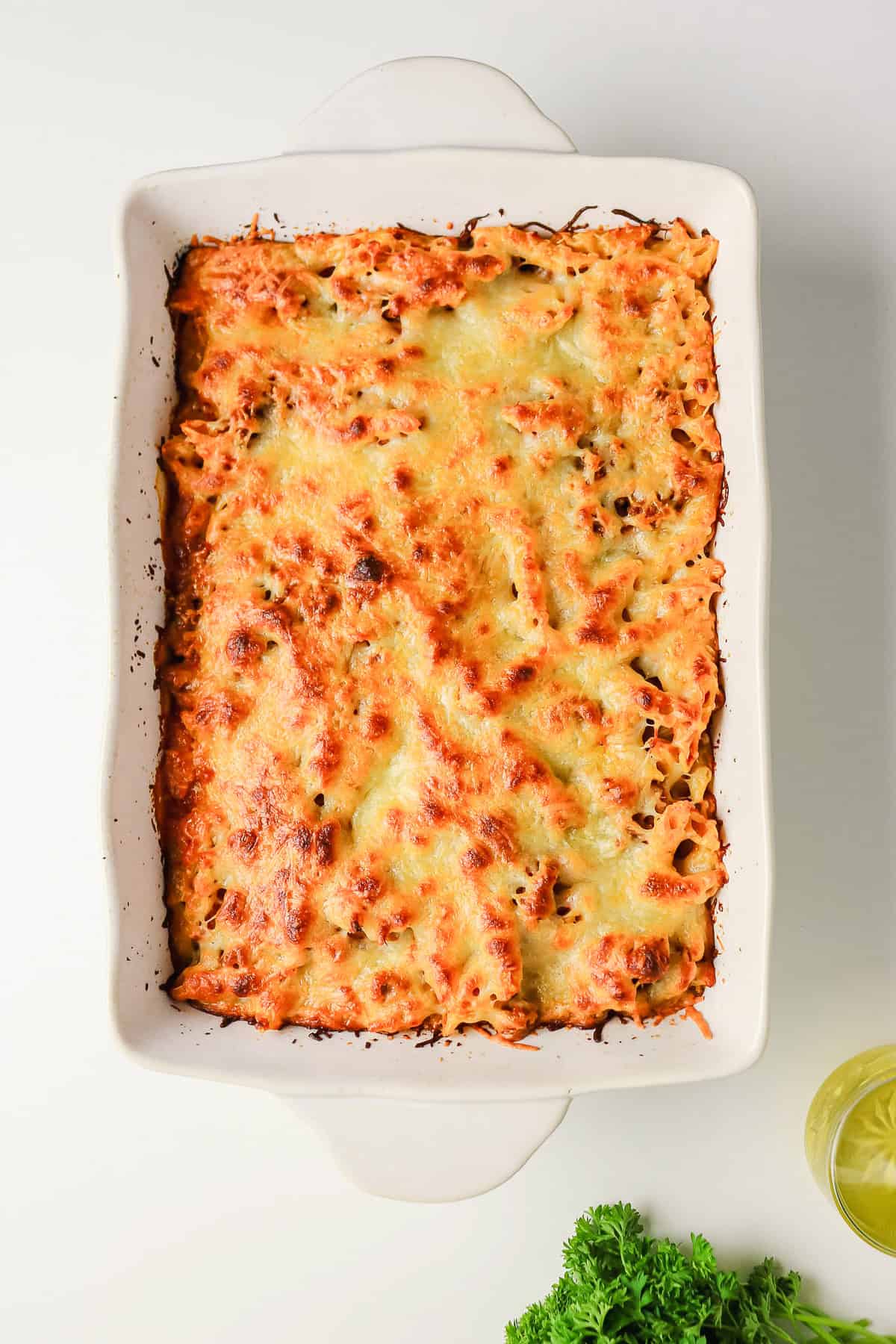 Sausage pasta bake with a golden-brown melted cheese topping in a white ceramic baking dish.